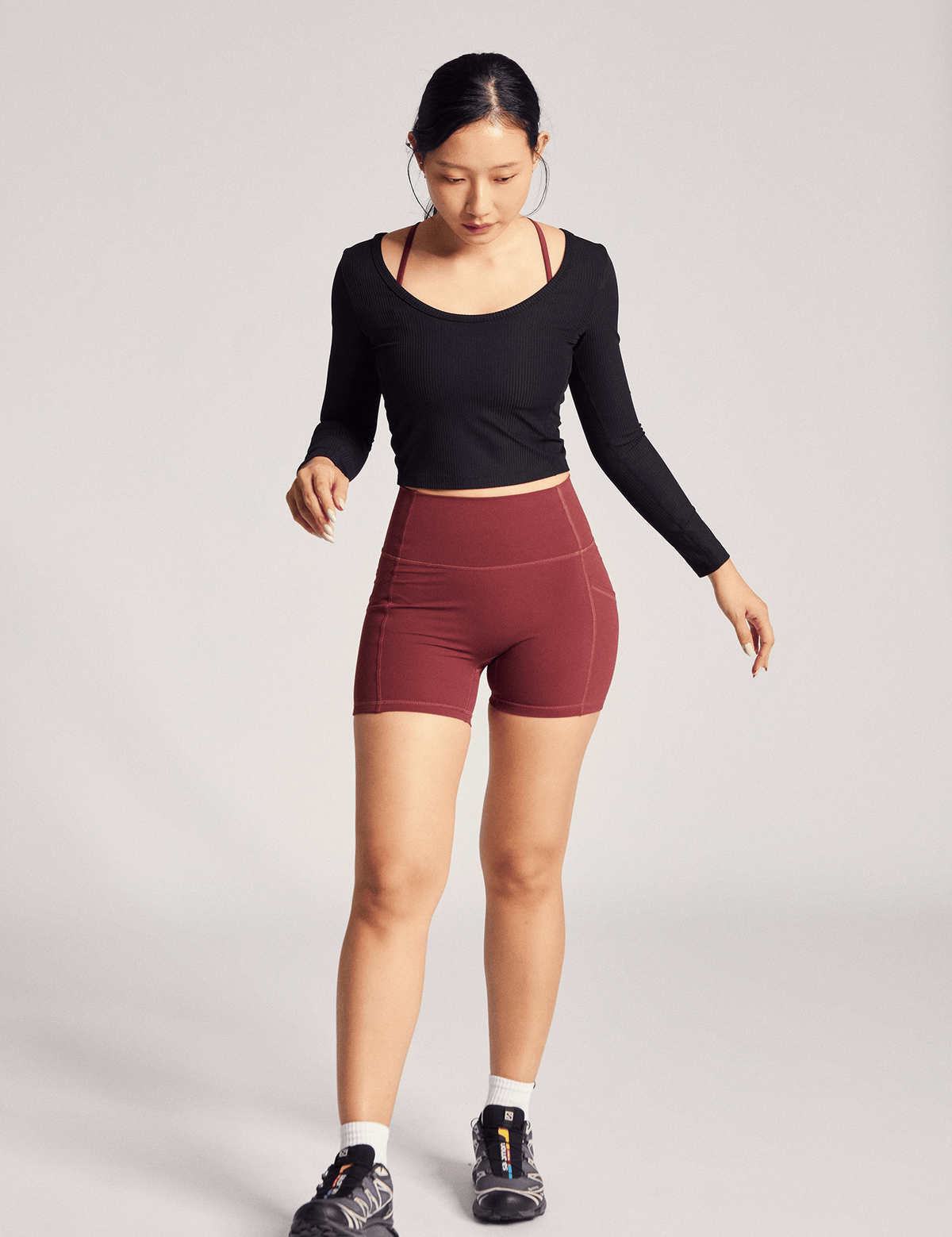 Anya Active Reversible Long Sleeve Top (Rib) in Black Sesame, full-length view with burgundy shorts and sneakers